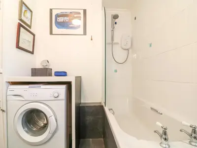 a bathroom with a washing machine and a bath tub at Jordan Cottage in Fowey