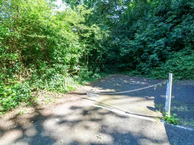 a road with a chain link fence and trees at Jordan Cottage in Fowey