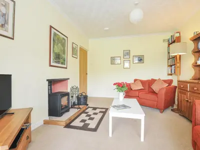 a living room with a red couch and a fireplace at Jordan Cottage in Fowey