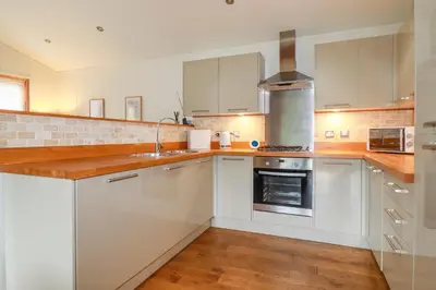 a kitchen with white cabinets and wooden counter tops at 10 Water's Edge in Looe