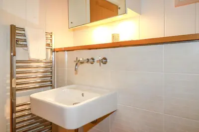 a white sink in a white tiled bathroom at 10 Water's Edge in Looe