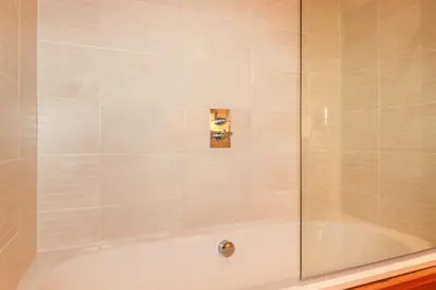 a shower with a glass door and a tub at 10 Water's Edge in Looe