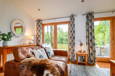 a living room with a leather couch and a window at 10 Water's Edge in Looe