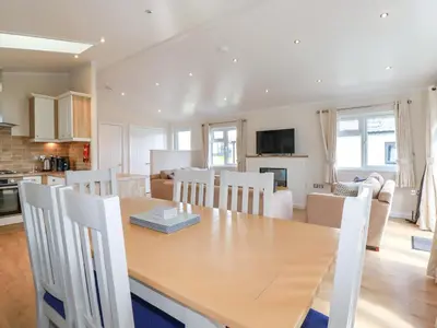 a kitchen and living room with a wooden table and chairs at 43 The Maples in St Austell