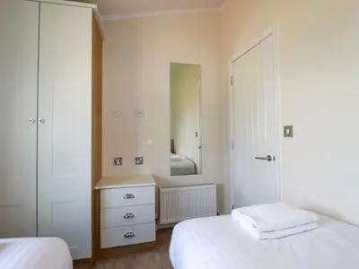 a bedroom with two beds and a mirror at 43 The Maples in St Austell
