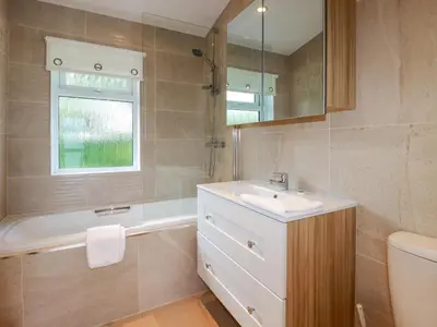 a bathroom with a sink and a tub and a mirror at 43 The Maples in St Austell