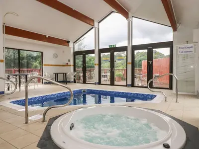 a large pool with a hot tub in a building at Jaspers Retreat, formerly known as Starfish Cottage in Falmouth