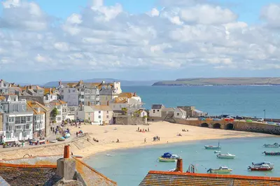 a beach with a group of people and boats in the water at Admiral Cottage in St Ives
