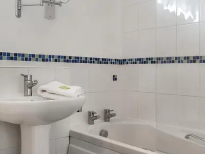 a white bathroom with a sink and a bath tub at Boobys Bay - Uk47554 in St Merryn