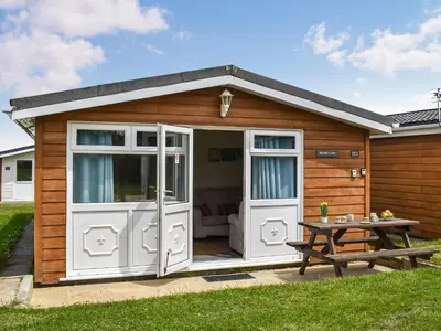 a wooden shed with a table and a picnic table at Boobys Bay - Uk47554 in St Merryn
