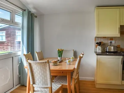 a small kitchen with a wooden table and chairs at Boobys Bay - Uk47554 in St Merryn