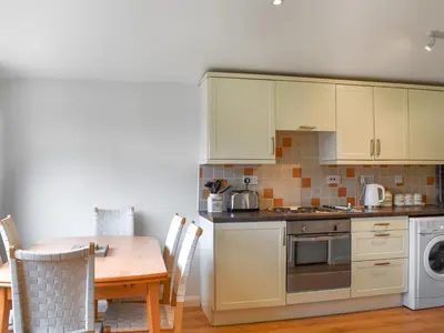 a kitchen with white cabinets and a table and a stove at Boobys Bay - Uk47554 in St Merryn
