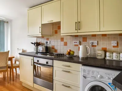 a kitchen with white cabinets and a stove top oven at Boobys Bay - Uk47554 in St Merryn