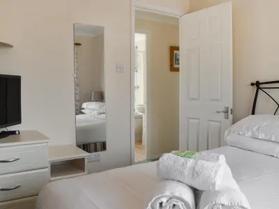 a bedroom with a bed with towels and a mirror at Stepper Point - Uk47568 in St Merryn