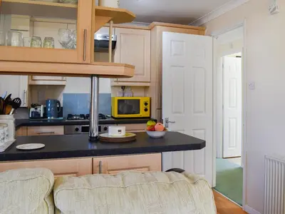 a kitchen with a black counter top and a yellow microwave at Stepper Point - Uk47568 in St Merryn