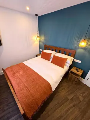 a bedroom with a large bed with a blue wall at Premier 2 - Stunning Suite with Breathtaking Seaside Views in St Ives