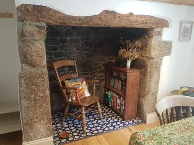 a room with a chair and a stone fireplace at Tranquil Cornish Heritage Retreat in Falmouth