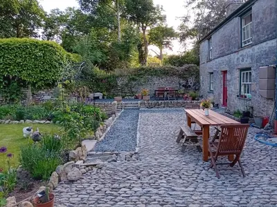 a stone patio with a wooden table and chairs at Tranquil Cornish Heritage Retreat in Falmouth