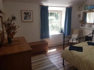 a bedroom with a bed and a window with blue curtains at Tranquil Cornish Heritage Retreat in Falmouth