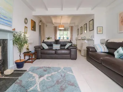 a living room with a leather couch and a fireplace at Connie's Cottage in Helston