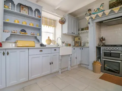 a kitchen with white cabinets and an oven at Connie's Cottage in Helston