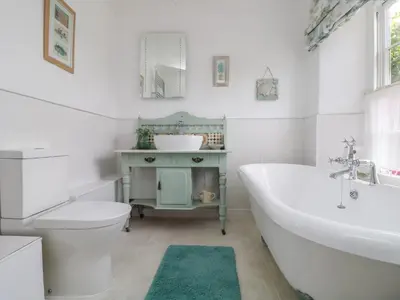a bathroom with a tub and a toilet and a sink at Connie's Cottage in Helston