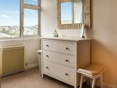 a bedroom with a dresser and a mirror and a stool at Trethvor in Perranporth
