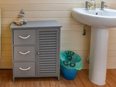 a bathroom with a sink and a cabinet next to a sink at Trethvor in Perranporth