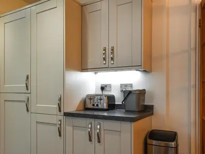 a kitchen with white cabinets and a coffee maker on a counter at Trethvor in Perranporth
