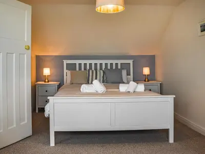 a bedroom with a large white bed with two lamps at Trethvor in Perranporth