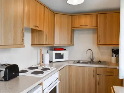 a kitchen with wooden cabinets and a white microwave at Gunner Head - Uk47557 in St Merryn