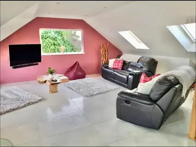 a living room with two leather chairs and a flat screen tv at Harber Rise House in Carlyon Bay