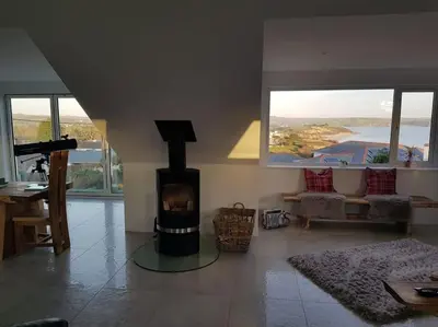 a living room with a fireplace with a view at Harber Rise House in Carlyon Bay