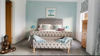 a bedroom with a large bed with a tufted headboard at Harber Rise House in Carlyon Bay