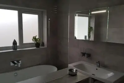 a bathroom with a tub and a sink and a mirror at Harber Rise House in Carlyon Bay