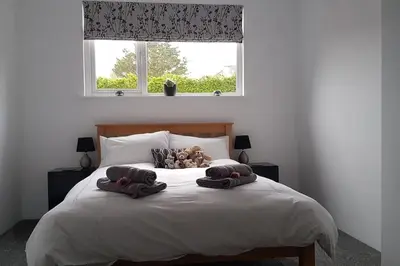 a bed with two pillows and a teddy bear on it at Harber Rise House in Carlyon Bay