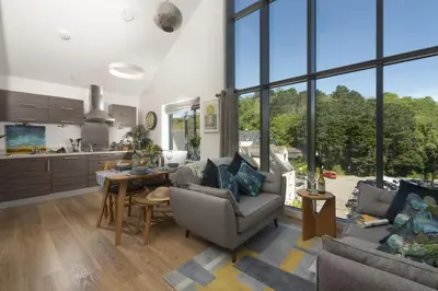 a living room with a table and chairs and a kitchen at Landing View Fowey Penthouse in Fowey