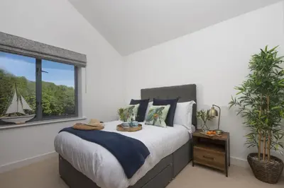 a bedroom with a bed and a window with a sailboat at Landing View Fowey Penthouse in Fowey