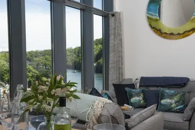 a living room with a couch and a table with flowers at Landing View Fowey Penthouse in Fowey