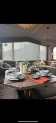 a table with plates and wine glasses on it at Cornwall caravan in Crantock