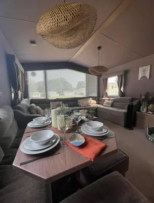 a table in a living room with plates and wine glasses at Cornwall caravan in Crantock