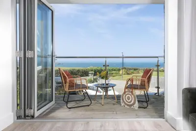 a patio with chairs and a table with a view of the ocean at Sea Breeze, Newquay in Newquay