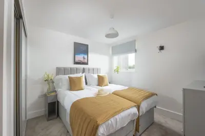 a white bedroom with a large bed with yellow pillows at Sea Breeze, Newquay in Newquay