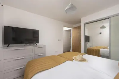 a bedroom with a bed and a tv and a mirror at Sea Breeze, Newquay in Newquay