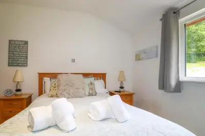 a bedroom with a bed with white sheets and a window at 3 Lake View in Looe
