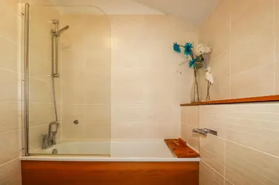 a bathroom with a tub and a shower with a vase of flowers at 3 Lake View in Looe