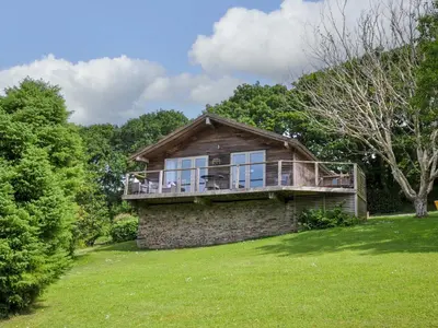 a house with a deck on top of a yard at 3 Lake View in Looe