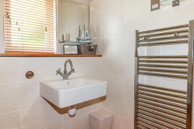 a white bathroom with a sink and a mirror at 3 Lake View in Looe