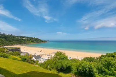a beach with people on the sand and the ocean at Viridian in Carbis Bay