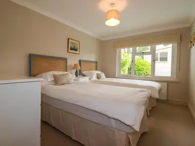 two beds in a bedroom with a window at 6 Trelawney Court in Wadebridge